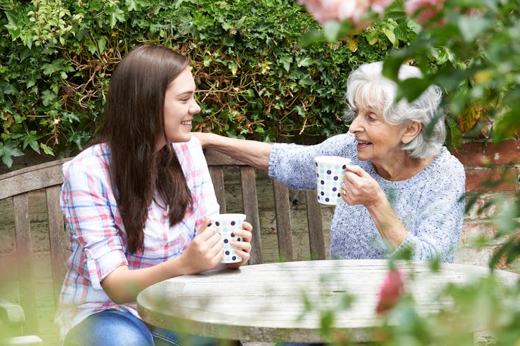 A teenager having a cup of tea with her grandmother