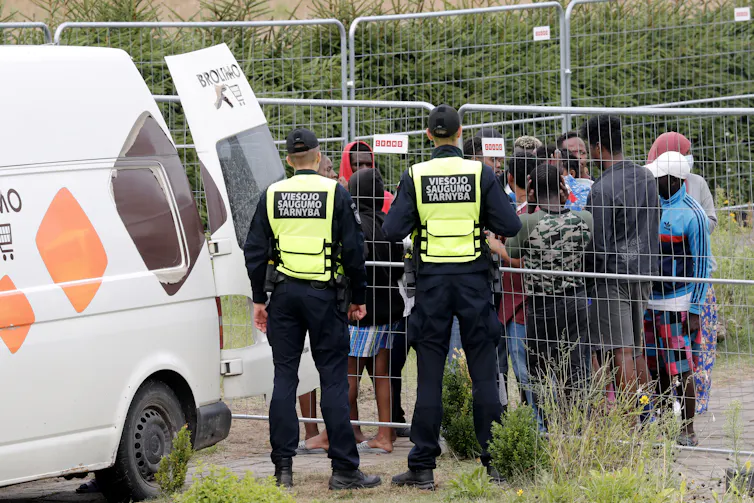 Detained migrants waiting in line for buying goods from an off-site store in a car at the migrant detention centre in Vydeniai, Lithuania
