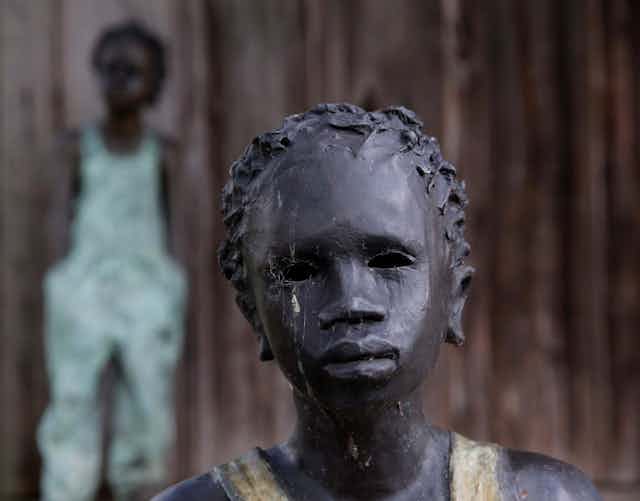 A statue of a slave child with another seen in the background.