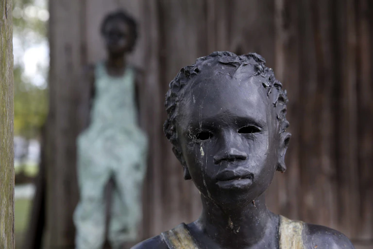 A statue of a slave child with another seen in the background.