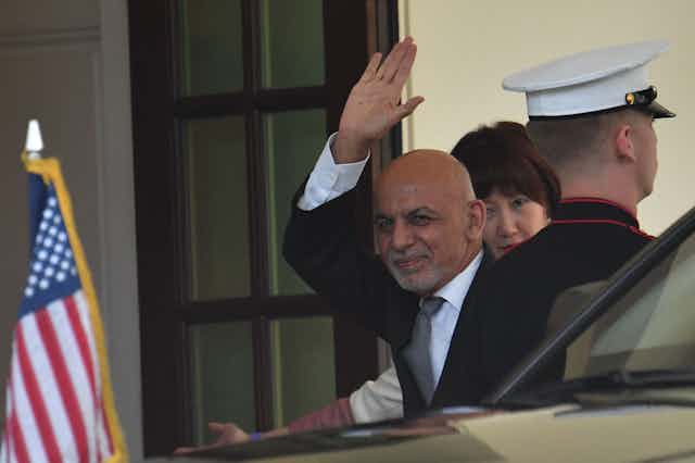 Ghani waves as he gets out of a car