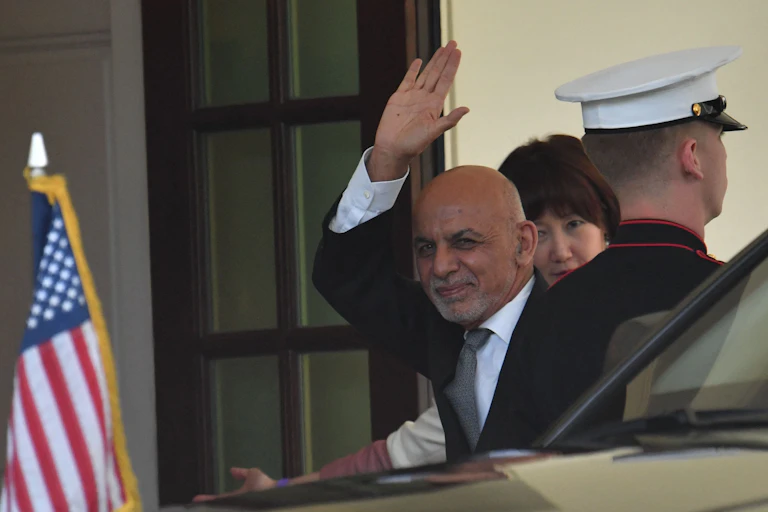 Ghani waves as he gets out of a car