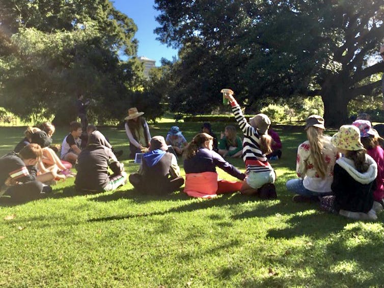 Children sitting in a circle on the grass, having a discussion.