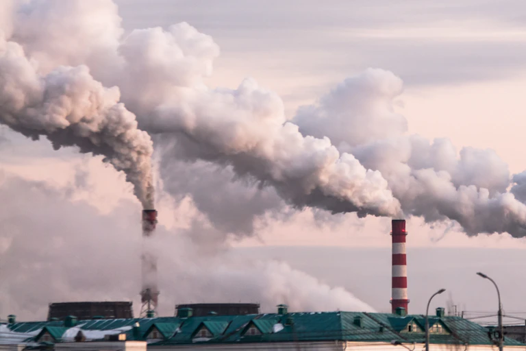 Three industrial chimneys belching white smoke.