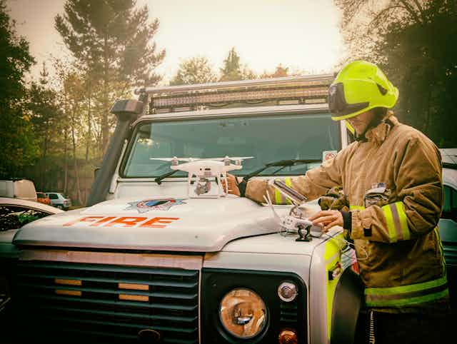 A firefighter prepping a drone on the hood of a fire truck