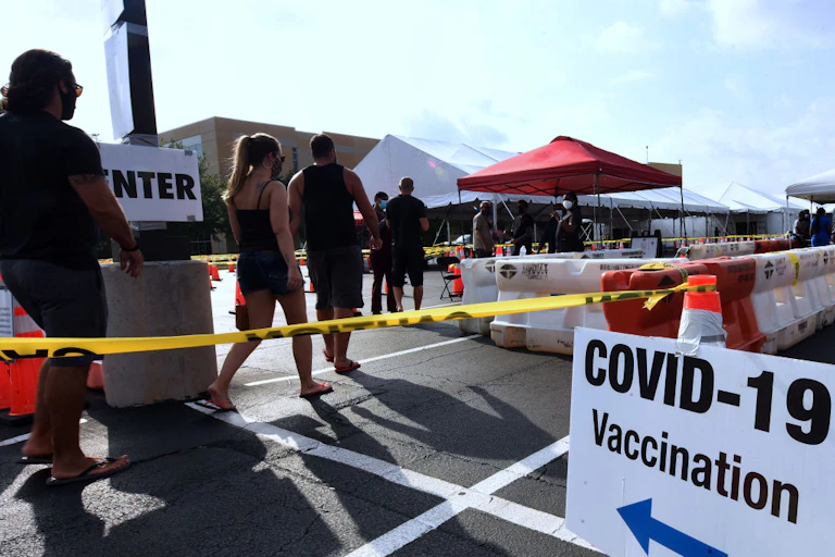 People standing in line at outdoors COVID-19 vaccination site.