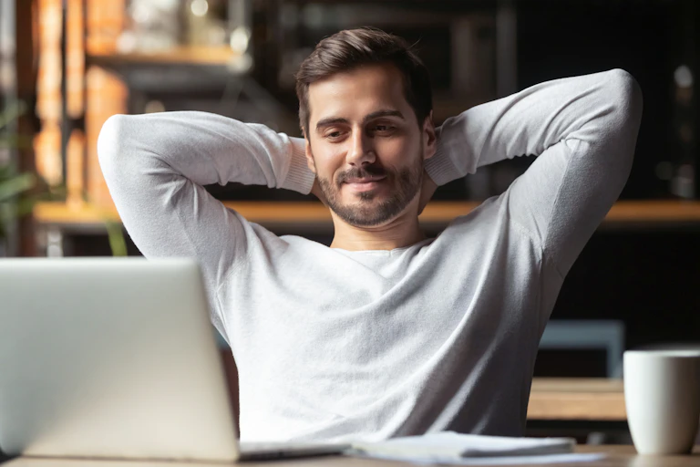 Jeune homme très relax devant son ordinateur, avec une tasse de café