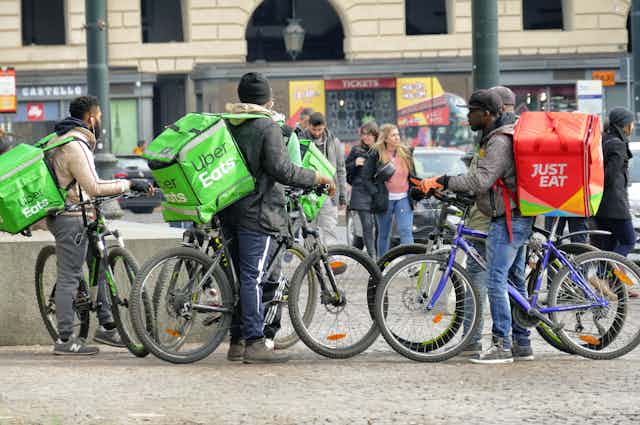 a group of cyclists with Uber eats and Just Eat delivery backpacks