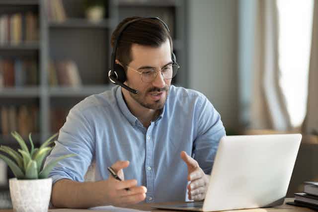 Teacher at the computer with headphones and microphone