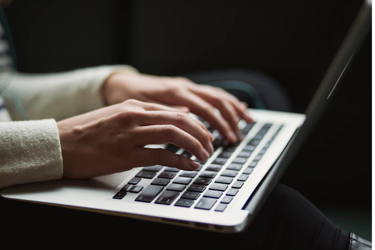 Hands typing on a laptop