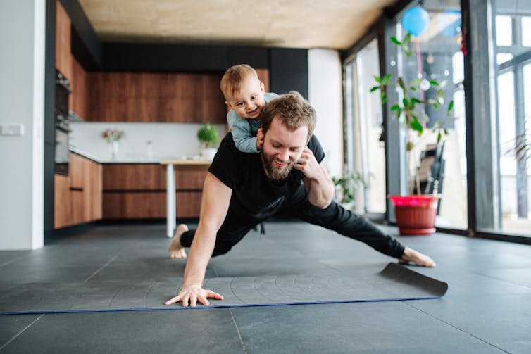 A man does a push-up with a kid on his back.