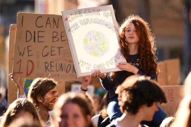 A young girl holds up a sign in a protest that reads 'Take care of the environment it's our future'