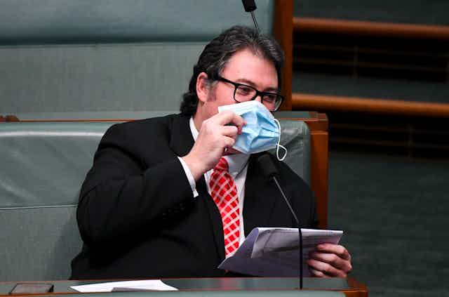 George Christensen holds a mask to his face