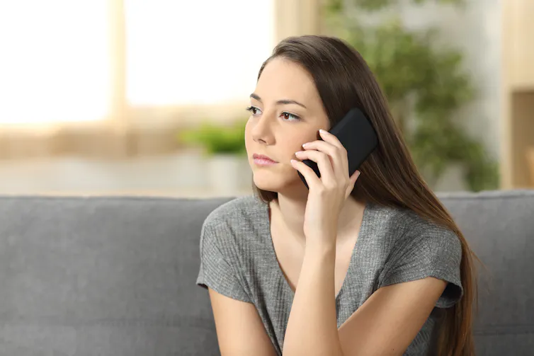 Serious woman talks on the telephone in her home.