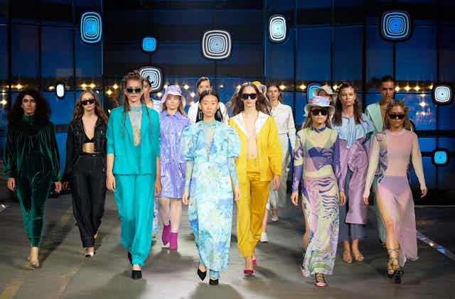 Models in brightly coloured clothes on a catwalk.
