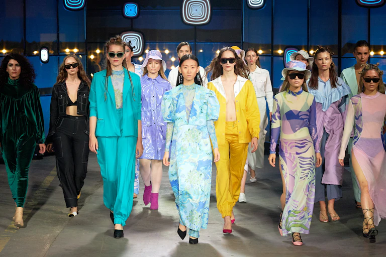 Models in brightly coloured clothes on a catwalk.