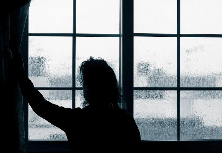 Woman looking out of window on rainy day.