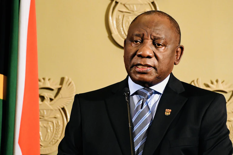 A man wearing a suit, shirt and tie speaks at a podium.