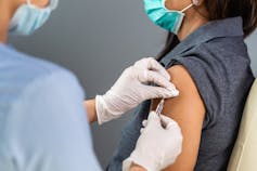 Mujer recibiendo la vacuna COVID en su brazo.