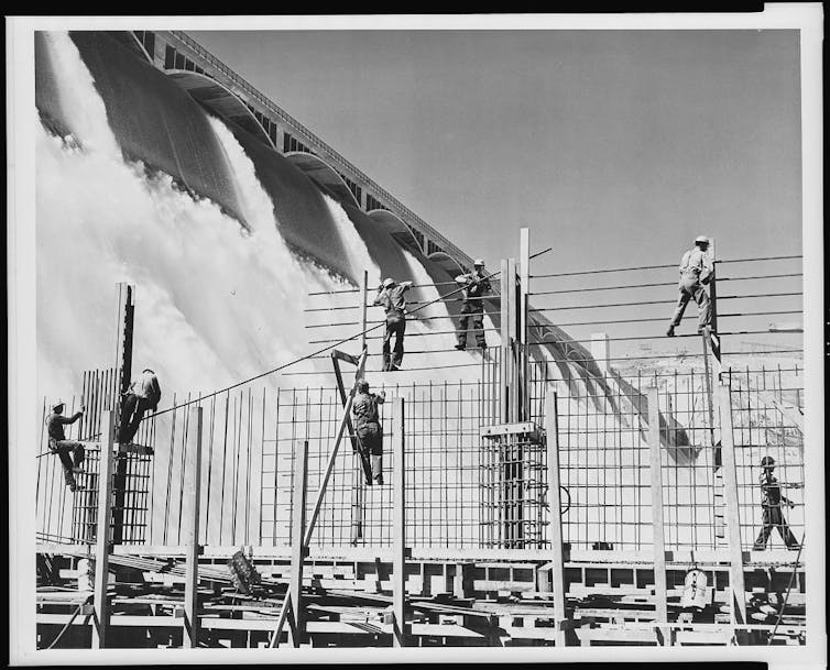 A black and white image of people working to build a large hydroelectric dam