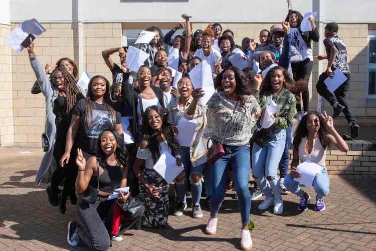 A group of students raise their hands and smile
