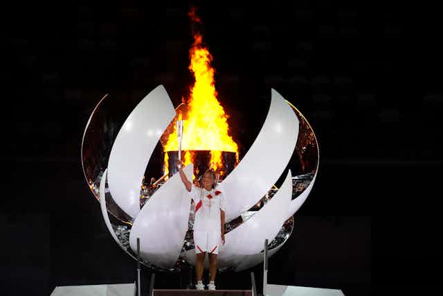 Naomi Osaka stands in front of the olympic cauldron in Japan after lighting the flame