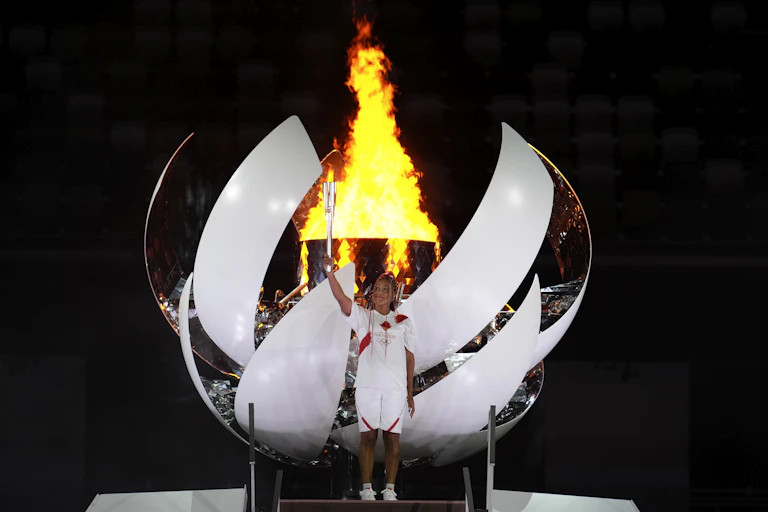 Naomi Osaka stands in front of the olympic cauldron in Japan after lighting the flame