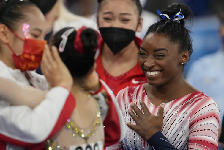 Simone Biles smiles excitedly wearing a unitard