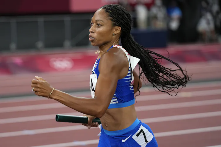 Woman wearing unitard runs holding baton