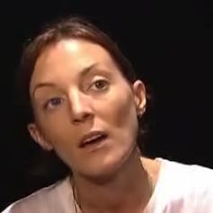 A woman with dark hair in a white shirt.