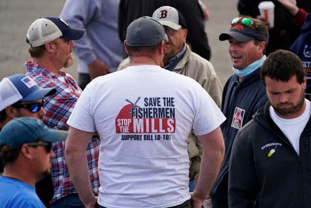 Man in T-shirt reading "Save the fishermen, stop the mills"
