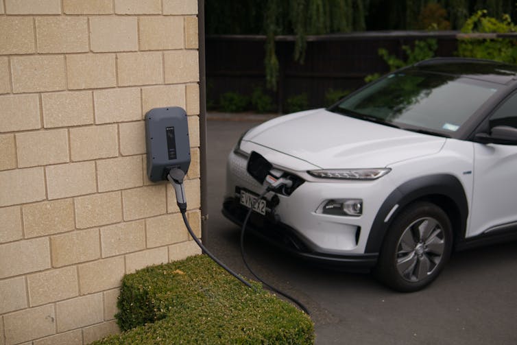 An electric vehicle charges along a house