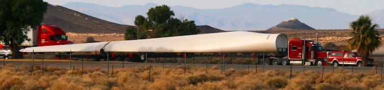 Large metal blade being transported on highway.