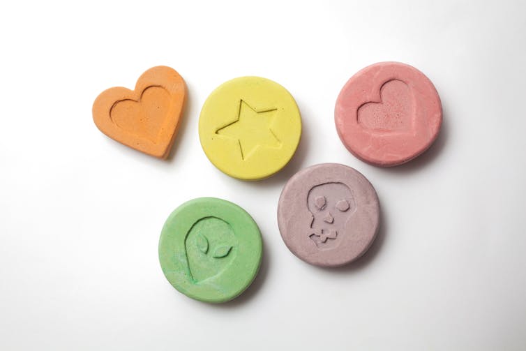 Five ecstasy tablets on a white background.