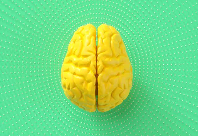 Digital generated image of artificial intelligence yellow brain on green background with circular dot pattern