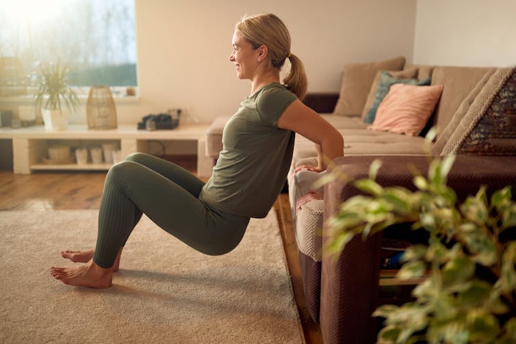 A woman does tricep dips at home.