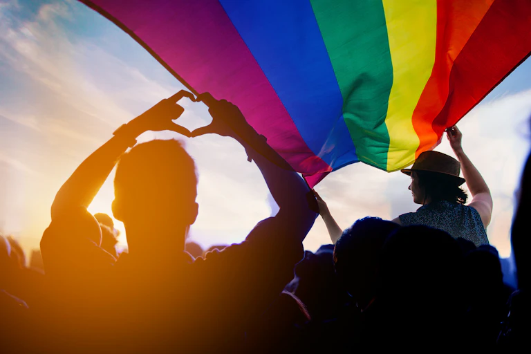 silhouetted people beneath gay pride flag