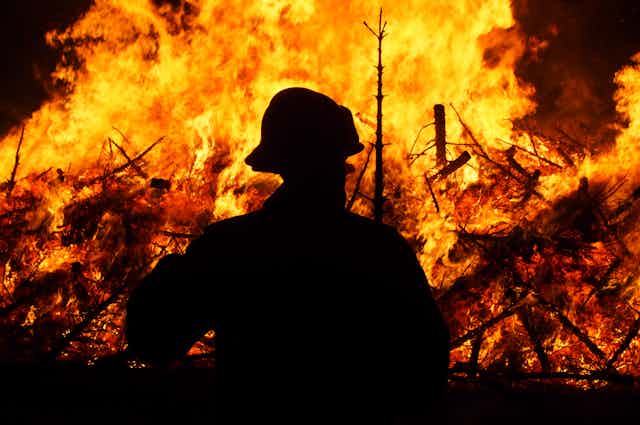 Silhouette of a firefighter in front of bonfire