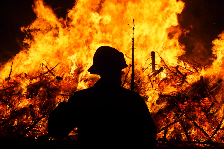 Silhouette of a firefighter in front of bonfire