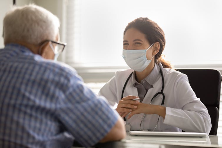 Specialist doctor at a desk talks to a patient, who sits facing her.