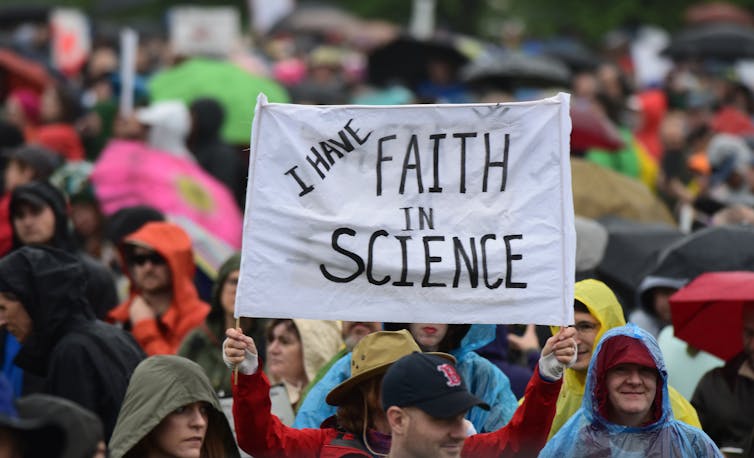 Person in crowd holds sign