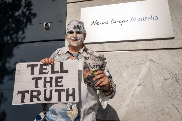 man holding sign reading 'Tell the Truth'