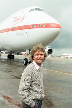 Richard Branson standing in front of a Virgin Atlantic plane
