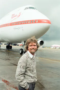 Richard Branson standing in front of a Virgin Atlantic plane