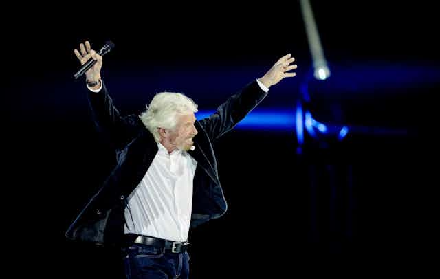 Richard Branson with his arms in the air
