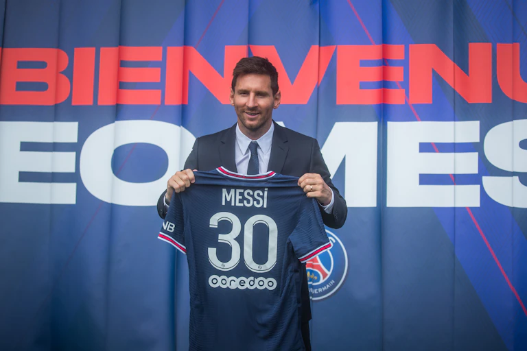Messi holds up his new team shirt.