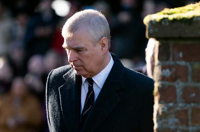 Prince Andrew with his head tilted downwards and a solemn expression.