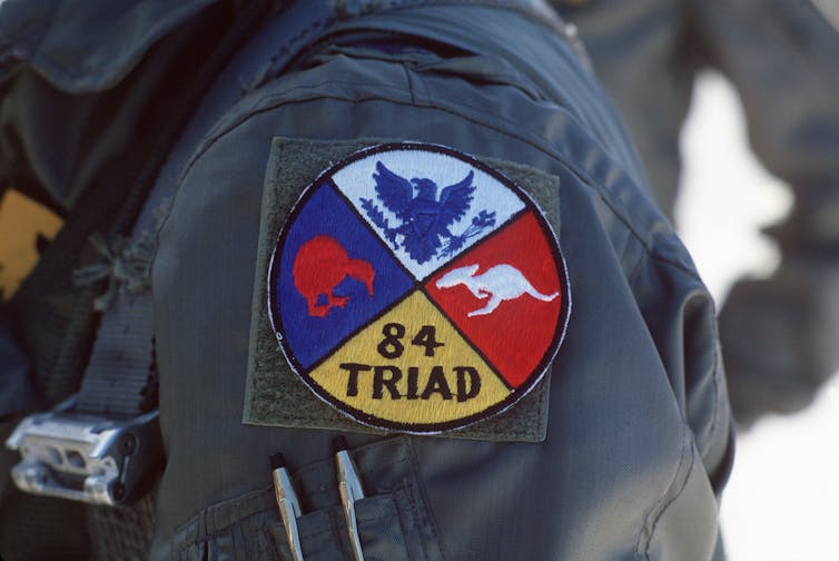 A circular military patch showing an eagle, a kiwi and a kangaroo