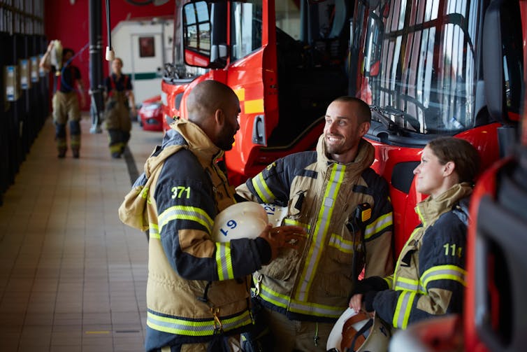 Firefighters dressed in uniforms, talking at fire station