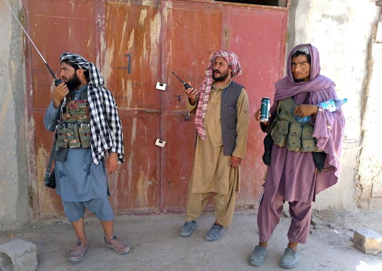 Three Taliban fighters stand guard at a checkpoint